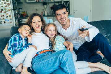 Happy family with two children watching television